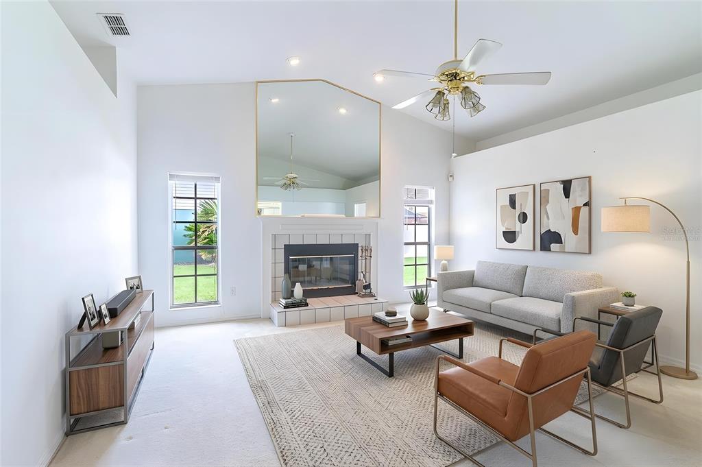 A living room features a fireplace with a large mirror, a ceiling fan, and furniture — 699 HUNTERS RUN BOULEVARD, LAKELAND, FL