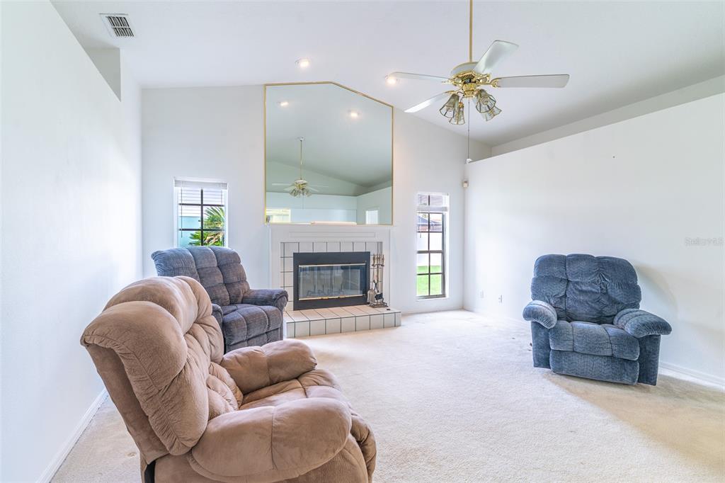A living room features a fireplace with a large mirror above and three recliner chairs — 699 HUNTERS RUN BOULEVARD, LAKELAND, FL