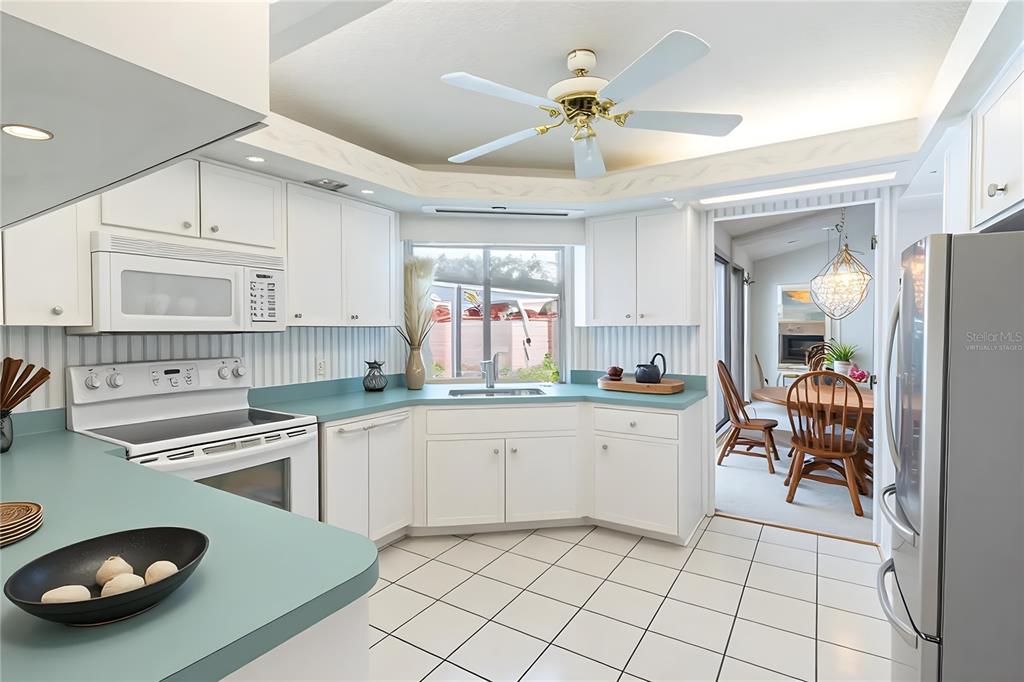 A kitchen with white cabinets, teal countertops, white tile floors, and a ceiling fan — 699 HUNTERS RUN BOULEVARD, LAKELAND, FL