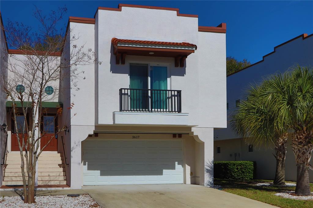 A two-story white stucco townhouse features a ground-level garage and a second-story balcony — 3617 BAY HEIGHTS WAY, TAMPA, FL