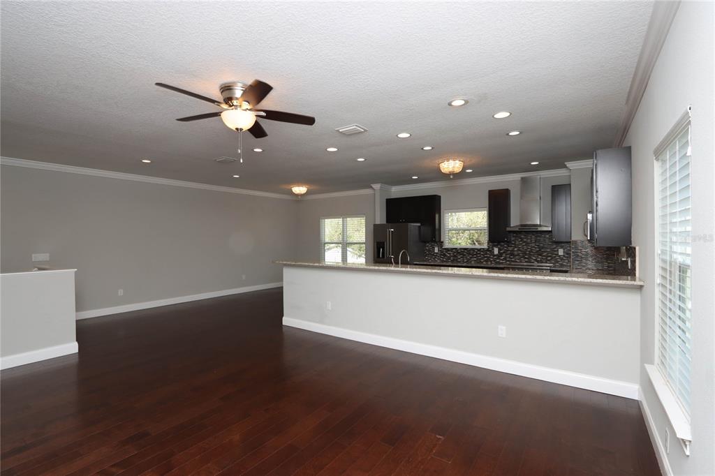 An open-concept kitchen and living area featuring dark wood floors and dark cabinetry — 3617 BAY HEIGHTS WAY, TAMPA, FL