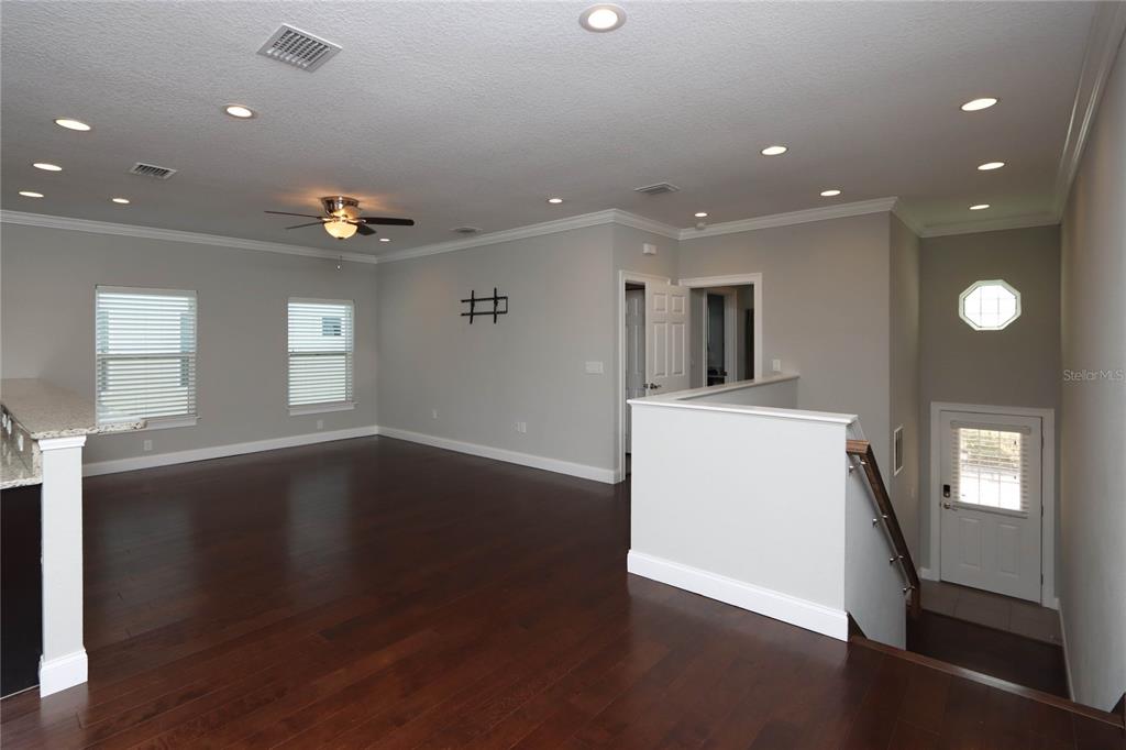 An open living area features dark hardwood floors, recessed lighting, and a staircase with railing — 3617 BAY HEIGHTS WAY, TAMPA, FL