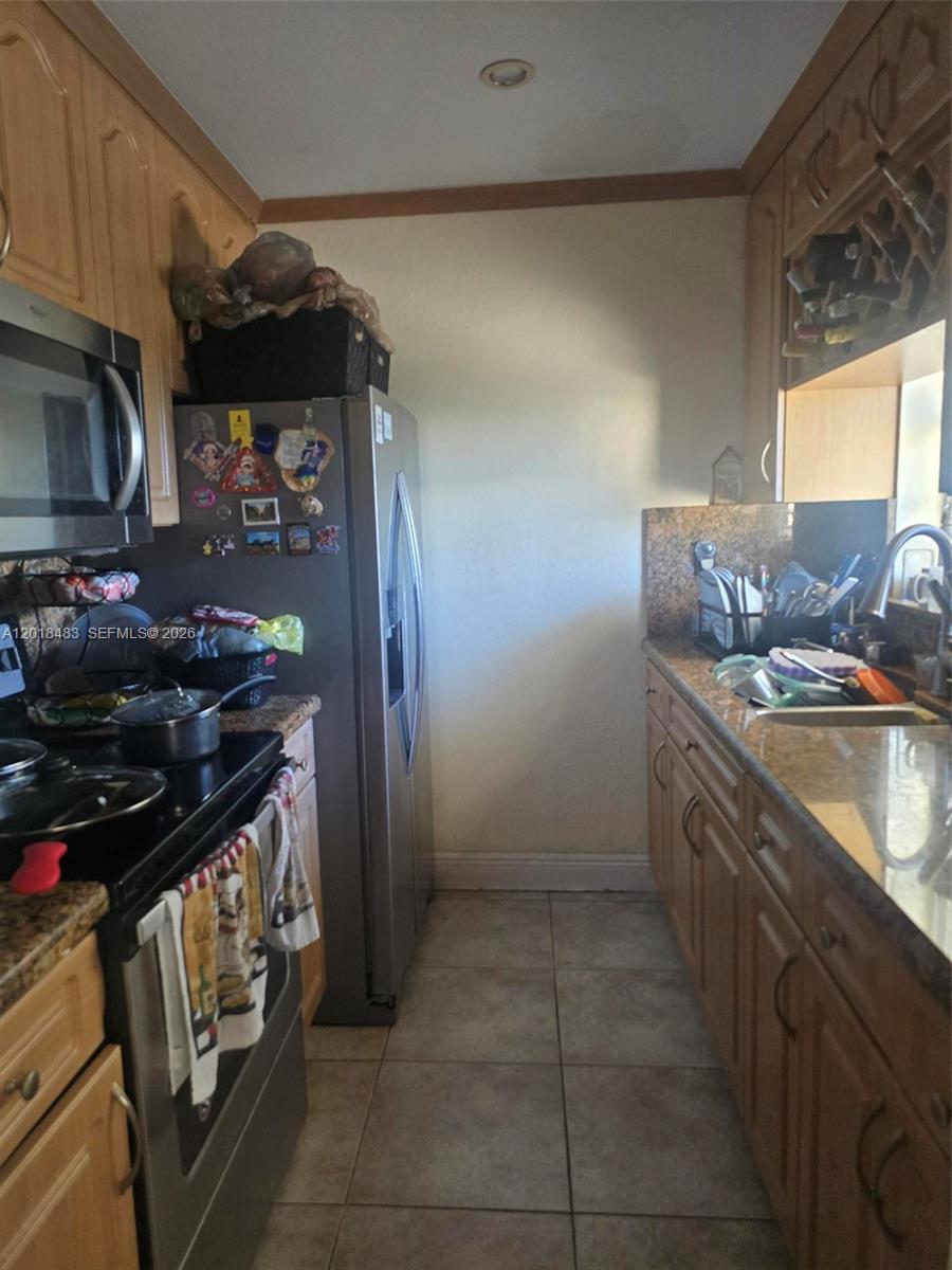A galley kitchen features wood cabinets, granite countertops, stainless steel appliances, and tile flooring — 10106 SW 20th St, Miami FL 33165, MIAMI, FL