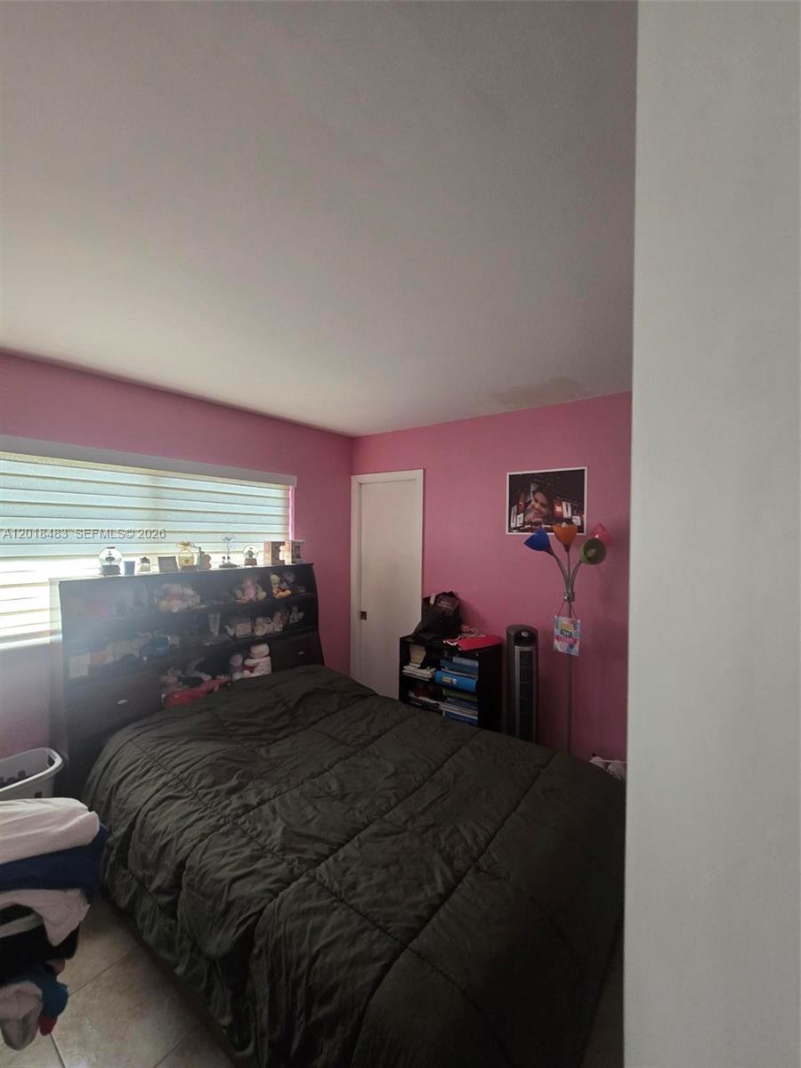 A bedroom features pink walls, a dark bed frame with shelving, and a window with blinds — 10106 SW 20th St, Miami FL 33165, MIAMI, FL