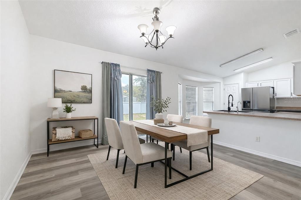 A dining area features a wooden table, four chairs, a console table, and sliding glass doors — 13117 SW 33RD TERRACE, OCALA, FL