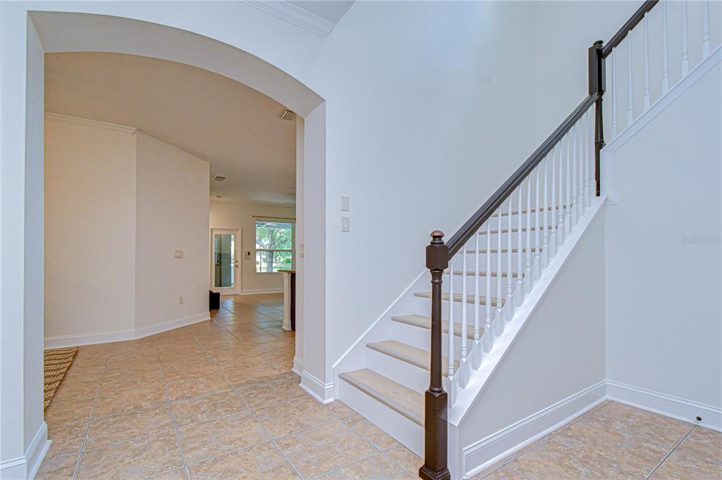 An entryway features light-colored tile flooring, a carpeted staircase with a dark wood railing — 5301 MATCH POINT PLACE, LITHIA, FL