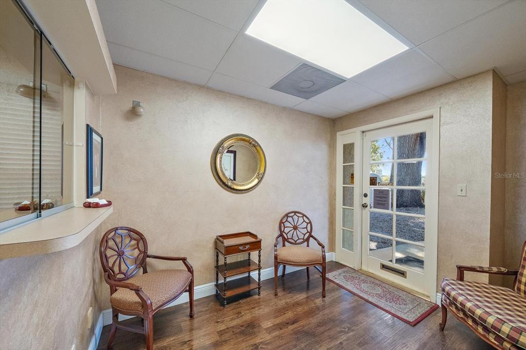 A waiting room features wood-look flooring, three chairs, a small side table, and a mirror — 1521 TAMIAMI TRAIL S UNIT 3A, VENICE, FL