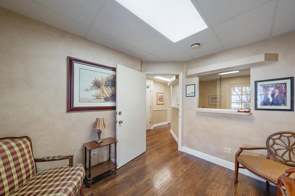 A waiting room features wood-look flooring, two chairs, a side table, and a service window — 1521 TAMIAMI TRAIL S UNIT 3A, VENICE, FL