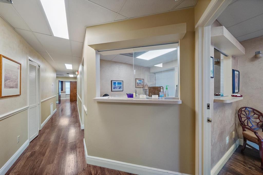 A hallway with wood-look flooring leads past a reception window into an office space — 1521 TAMIAMI TRAIL S UNIT 3A, VENICE, FL