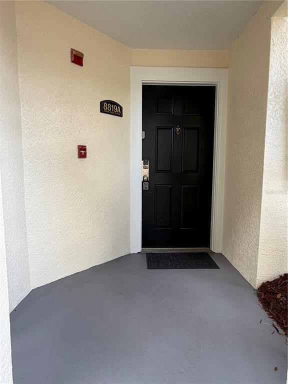 A black front door with a house number sign is set in a stucco entryway — 8819 GRAND PALMS CIRCLE UNIT A, KISSIMMEE, FL