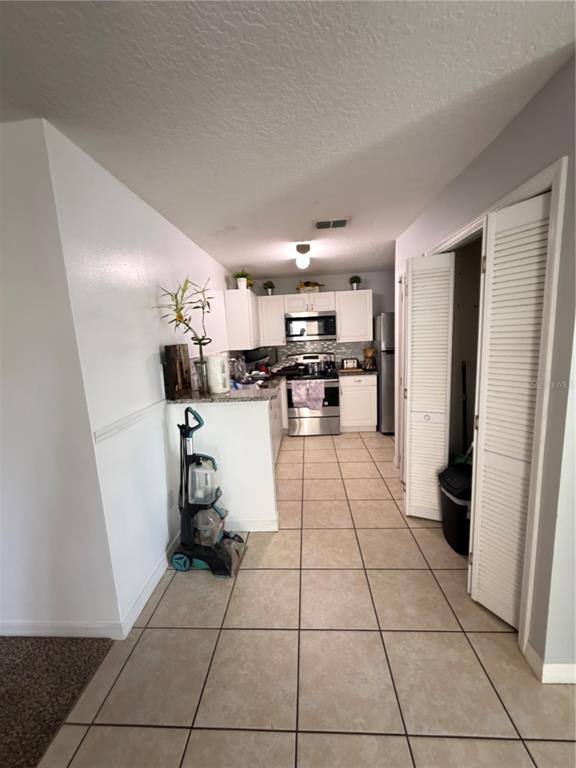 A kitchen features white cabinets, stainless steel appliances, and light-colored tile flooring — 8819 GRAND PALMS CIRCLE UNIT A, KISSIMMEE, FL