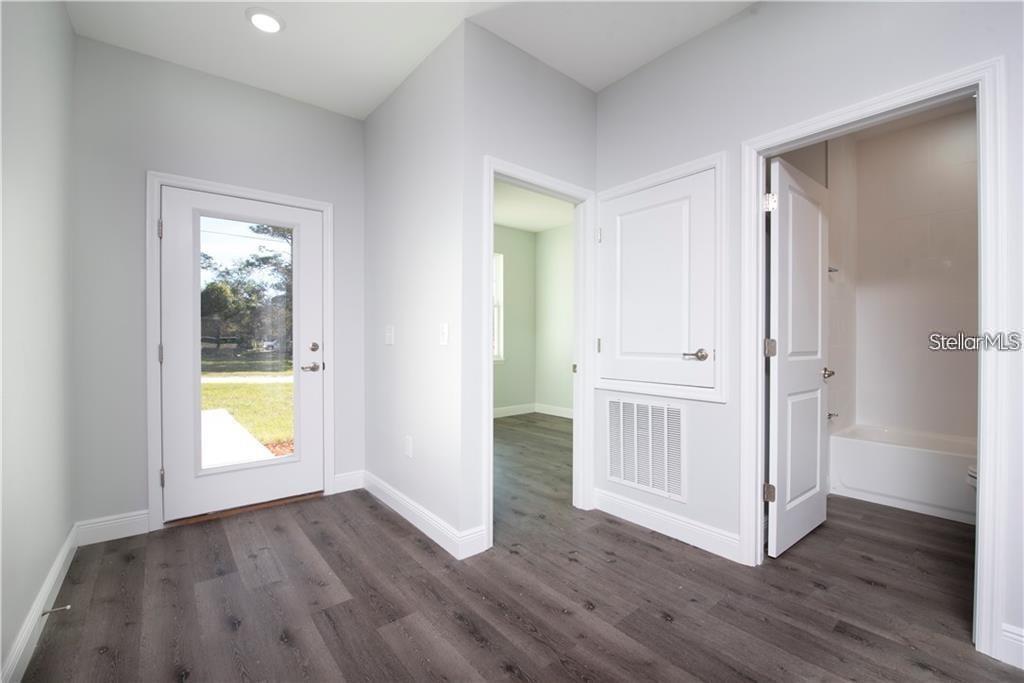 A room with gray wood-look flooring, a glass-paneled door, an interior doorway, and a bathroom — 574 GERALDINE DRIVE, DELTONA, FL