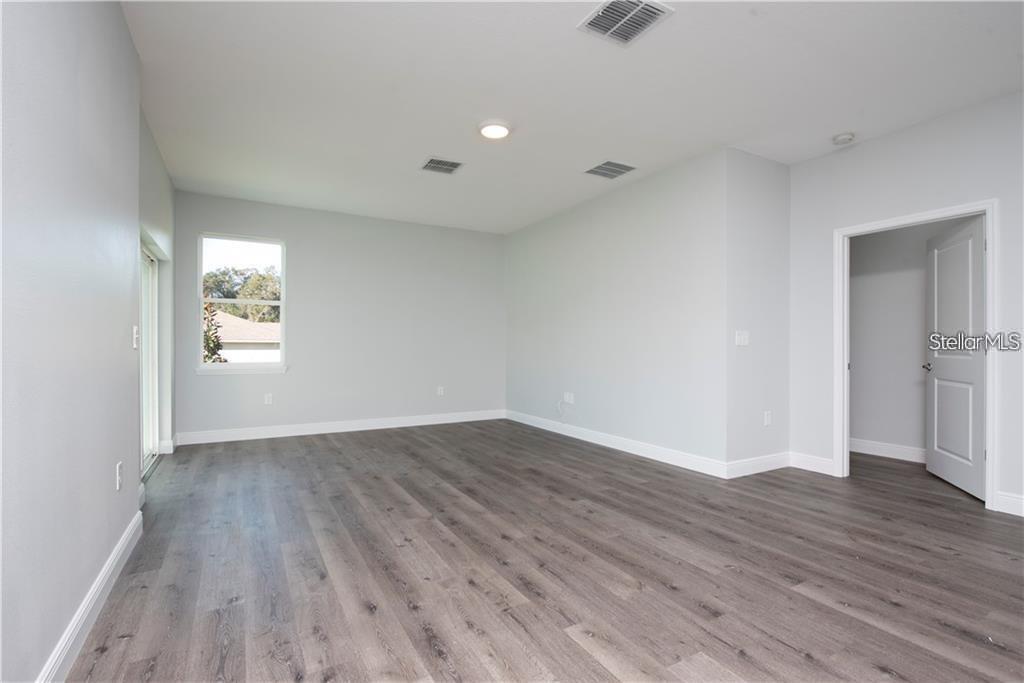 An empty room features light gray walls, wood-look flooring, a window, and an open doorway — 574 GERALDINE DRIVE, DELTONA, FL