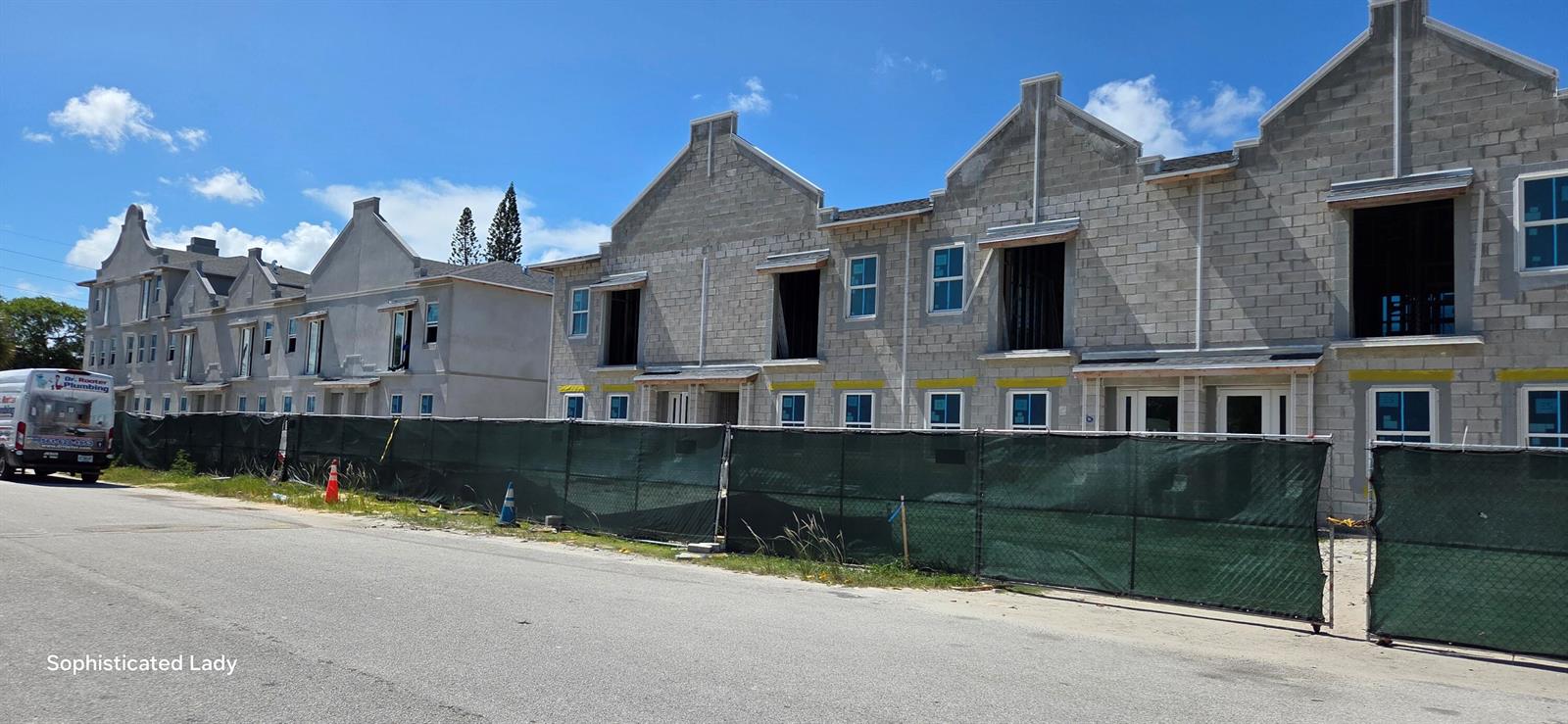 A row of townhouses under construction with exposed concrete blocks and a green privacy fence — 132 W 11th Street, Riviera Beach FL 33404, RIVIERA BEACH, FL