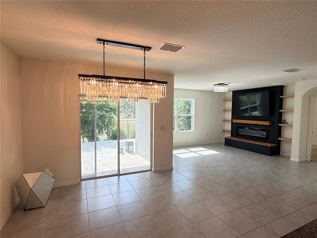 A dining area with a crystal chandelier leads to a living room with a fireplace — 2916 SUNRIDGE LOOP, ST CLOUD, FL