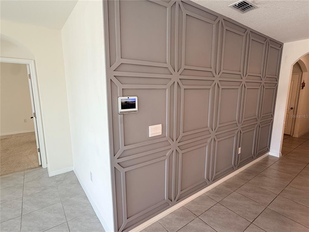 A gray wall features decorative geometric molding, a wall-mounted tablet, and a light switch — 2916 SUNRIDGE LOOP, ST CLOUD, FL