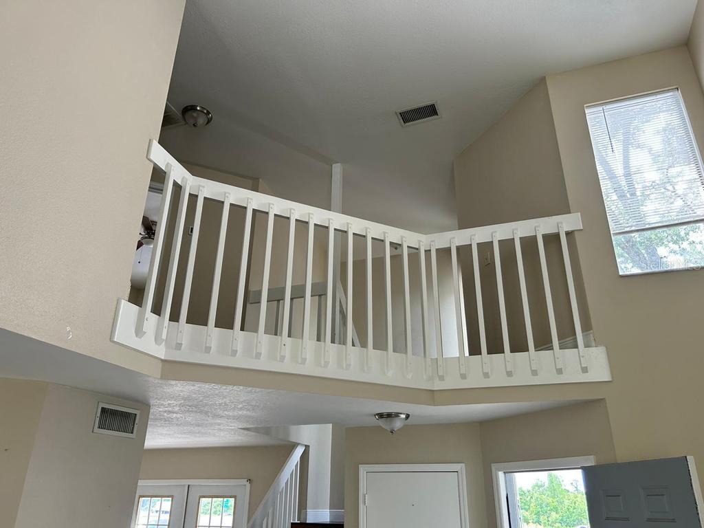 A view looking up at a white wooden balcony railing overlooking a living area — 222 CARPENTERS WAY UNIT 6, LAKELAND, FL