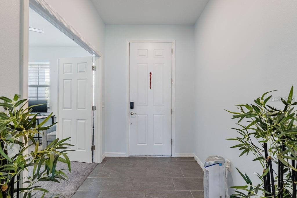 An entryway features gray tile flooring, a white front door, and a doorway to an office — 3319 CURLEW AVENUE, LEESBURG, FL