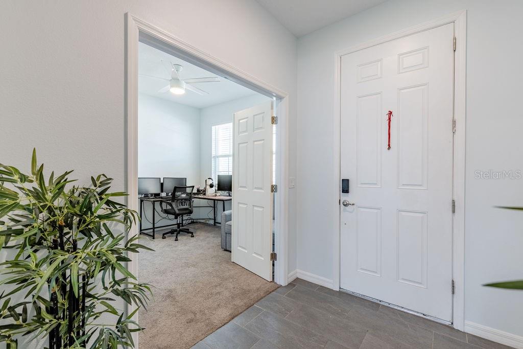 An entryway with tile flooring leads into a carpeted home office through double doors — 3319 CURLEW AVENUE, LEESBURG, FL