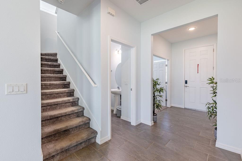 An entryway with tile flooring, a carpeted staircase, and a doorway leading to a bathroom — 3319 CURLEW AVENUE, LEESBURG, FL
