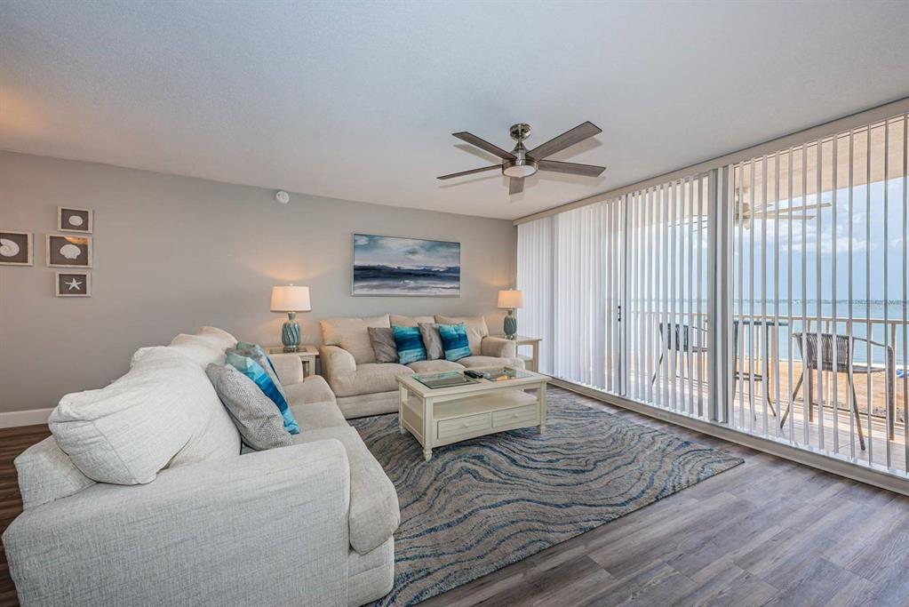 A living room features two beige sofas, a patterned area rug, and floor-to-ceiling balcony windows — 5151 ISLA KEY BOULEVARD S UNIT 220, ST PETERSBURG, FL