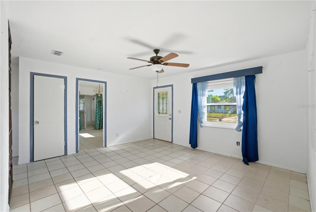A bright room with white walls, tiled floors, a ceiling fan, and a blue-trimmed door — 800 ORANGE GROVE DRIVE, ALTAMONTE SPRINGS, FL