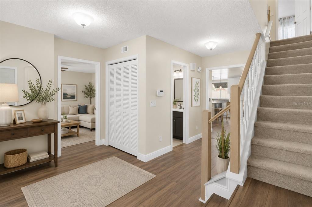 An entryway features wood-look flooring, a staircase with carpet, and doorways leading to other rooms — 10904 AUTUMN OAK PLACE, TAMPA, FL