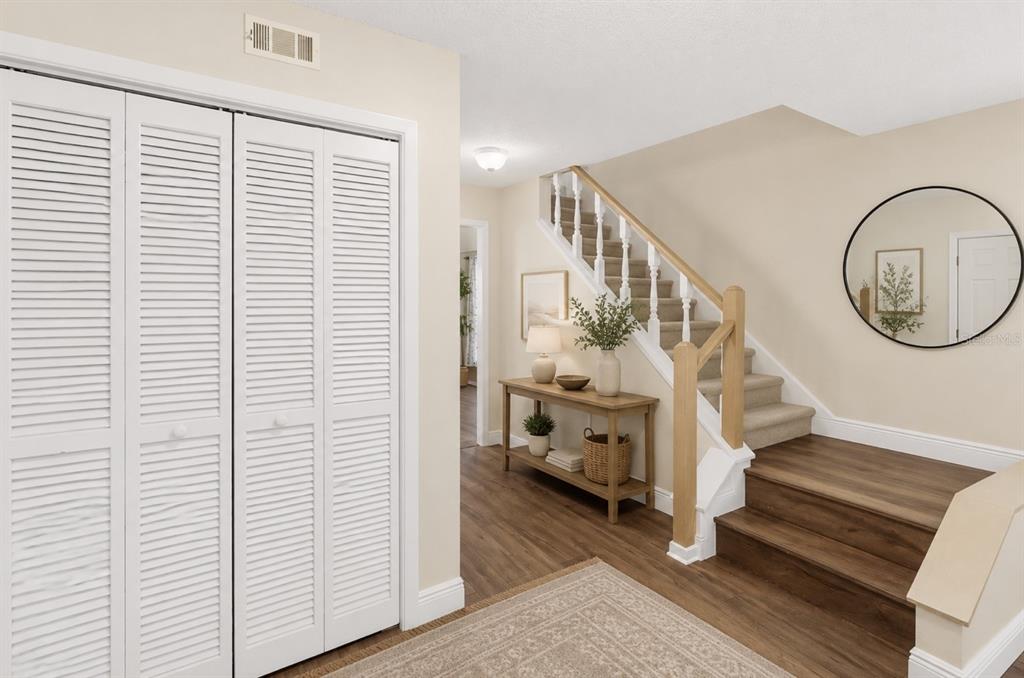 An entryway features a staircase with wood steps, a console table, and white louvered closet doors — 10904 AUTUMN OAK PLACE, TAMPA, FL