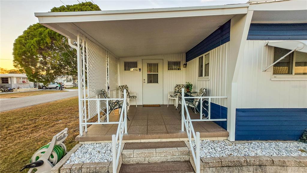 A covered front porch with white railings, outdoor furniture, and a door to a mobile home — 5227 BETTY STREET, ZEPHYRHILLS, FL