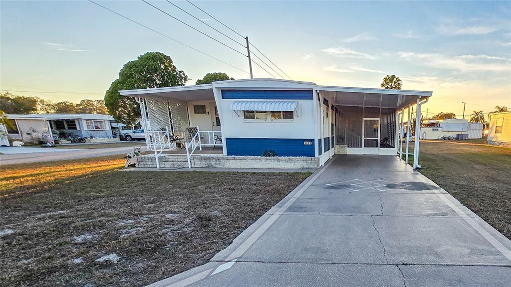 A single-story mobile home with a blue and white exterior, a carport, and a porch — 5227 BETTY STREET, ZEPHYRHILLS, FL