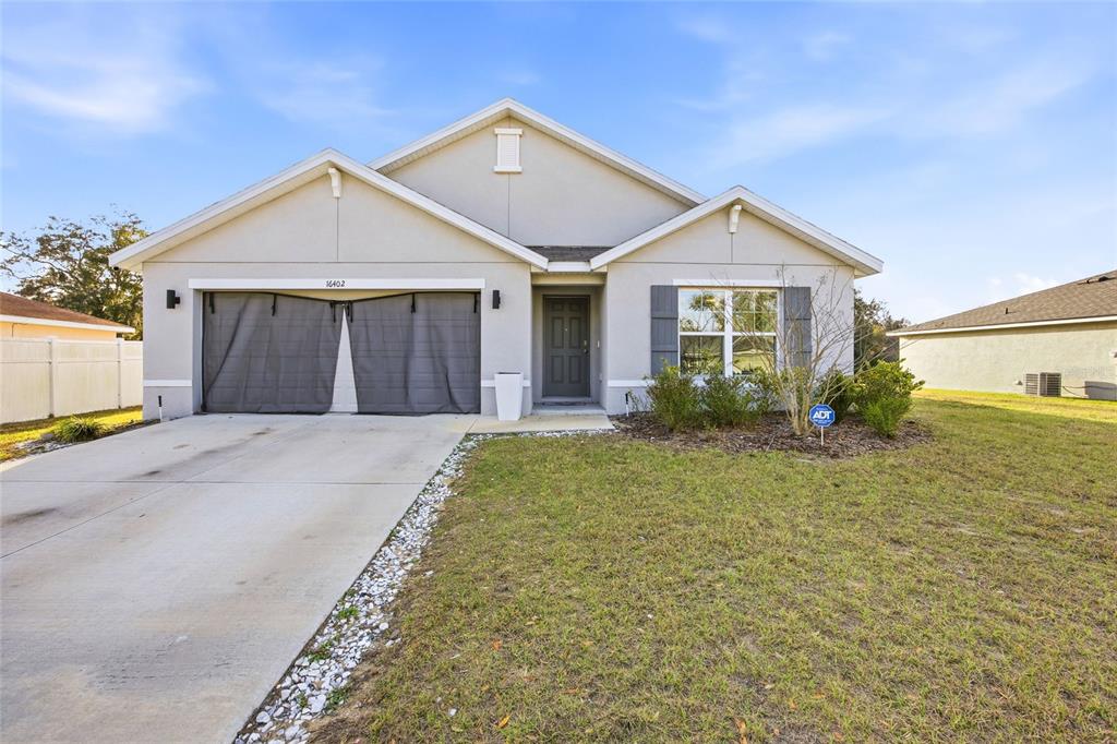 A single-story house with a concrete driveway, a garage screen, and a front entrance — 16402 SW 17TH TERRACE ROAD, OCALA, FL
