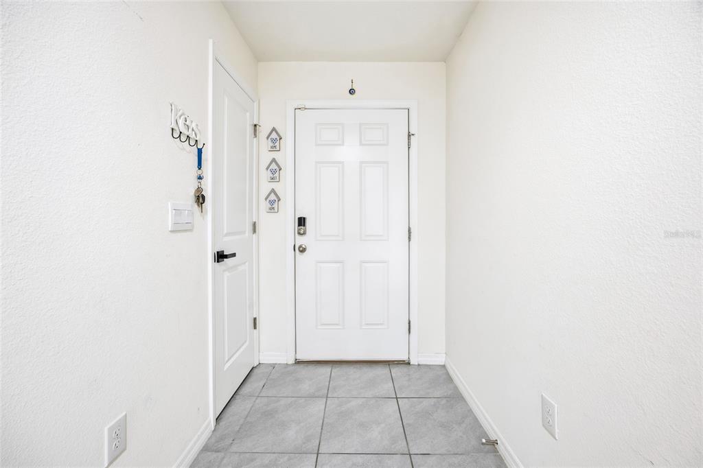 An entryway features a white front door, a side door, and light gray tiled flooring — 16402 SW 17TH TERRACE ROAD, OCALA, FL