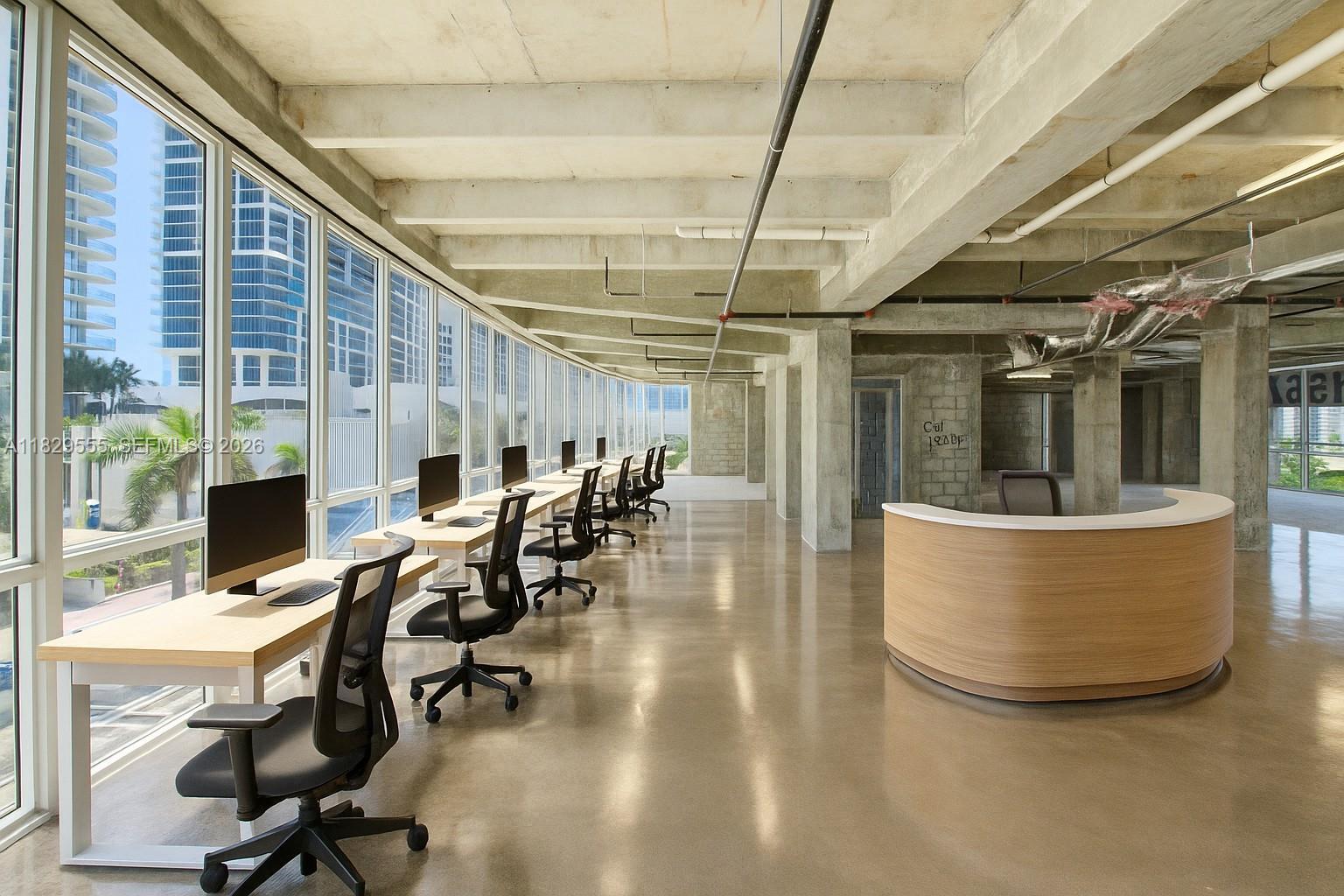 An open-plan office space features a curved wooden reception desk, rows of workstations, and floor-to-ceiling windows — 6930 Collins Ave # O1, Miami Beach FL 33141, MIAMI BEACH, FL