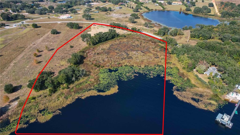 An aerial view shows a vacant, grassy waterfront lot outlined in red next to a lake — 0 CHERRY LAKE ROAD, GROVELAND, FL