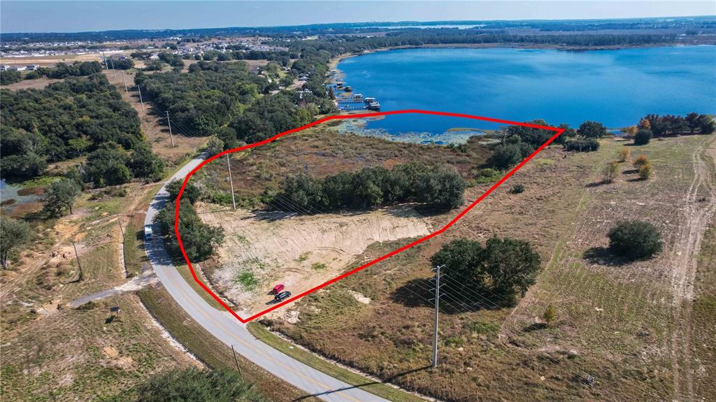 An aerial view shows a vacant, partially cleared lot bordering a lake and a road — 0 CHERRY LAKE ROAD, GROVELAND, FL