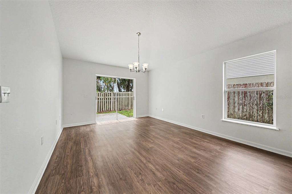 An empty room features light gray walls, wood-look flooring, a chandelier, and a sliding door — 332 MCKAY BOULEVARD, SANFORD, FL