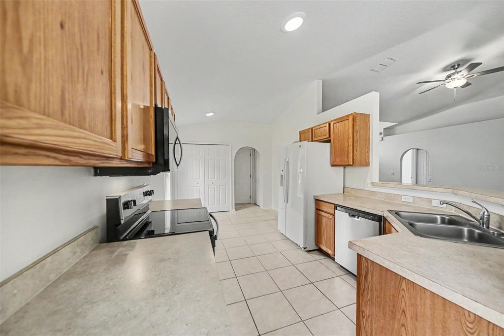 A kitchen features oak cabinets, white appliances, tile flooring, and a double-basin sink — 332 MCKAY BOULEVARD, SANFORD, FL