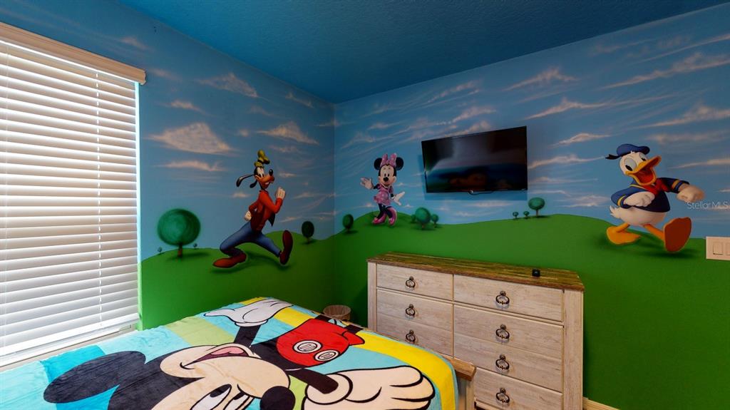 A bedroom features a Mickey Mouse-themed bedspread and walls painted with Disney character murals — 2438 TANGER DRIVE, KISSIMMEE, FL