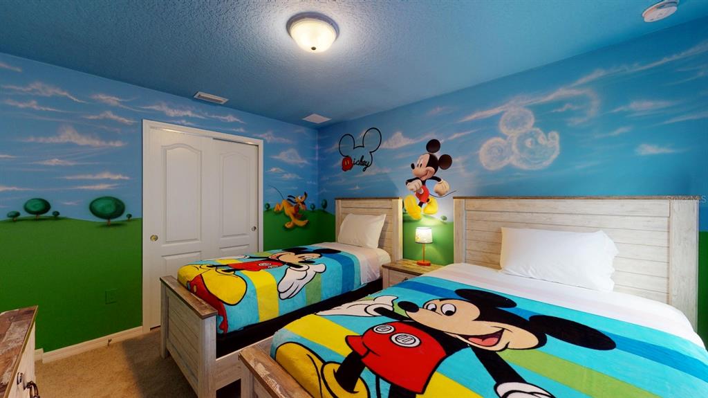 A bedroom features two twin beds with Mickey Mouse bedding and a mural-painted wall — 2438 TANGER DRIVE, KISSIMMEE, FL