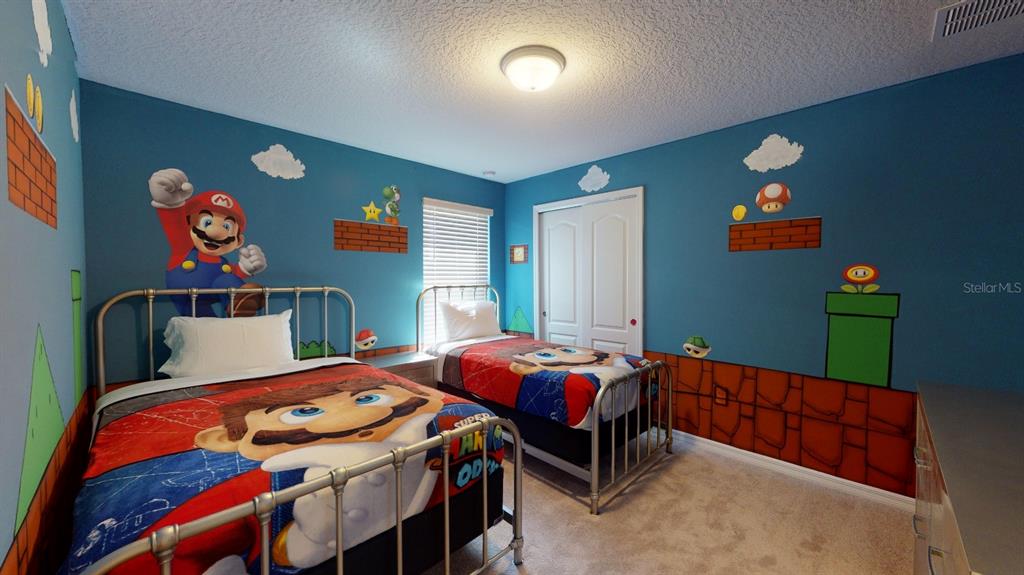 A bedroom with two twin beds features blue walls painted with Super Mario themed murals — 2438 TANGER DRIVE, KISSIMMEE, FL