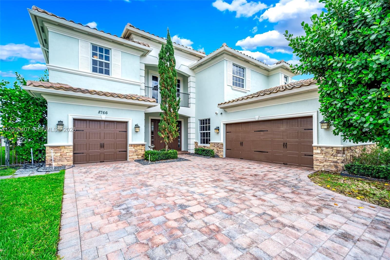 A two-story house with a light blue exterior, brown garage doors, and a paved driveway — 8766 Miralago Way, Parkland FL 33076, PARKLAND, FL