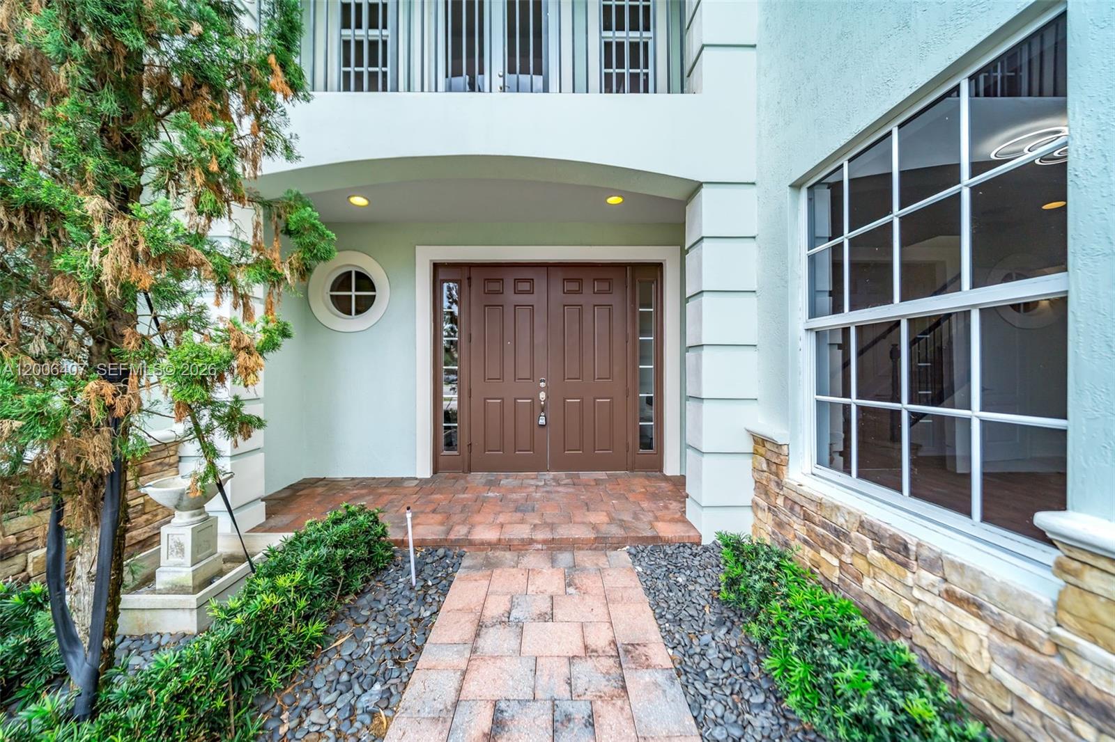 The exterior entrance features a brick walkway leading to double brown doors under a balcony — 8766 Miralago Way, Parkland FL 33076, PARKLAND, FL