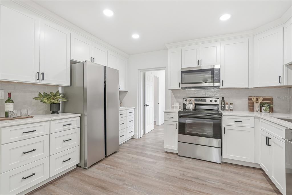 A kitchen with white cabinets, stainless steel appliances, and light wood-look flooring — 2534 19TH STREET S, ST PETERSBURG, FL
