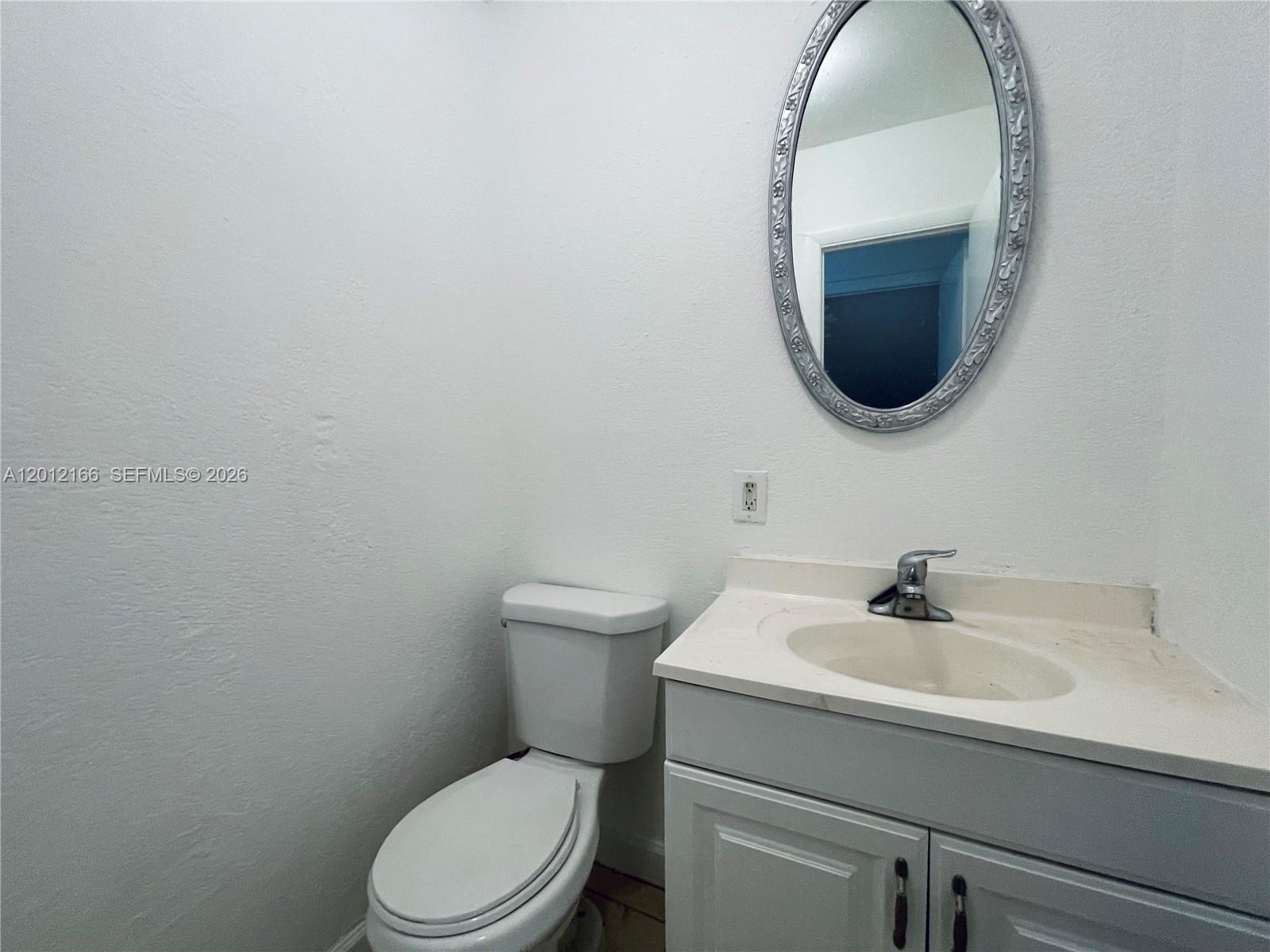 A small bathroom features a white vanity, a toilet, and an oval wall mirror — 825 NW 46th Ave # 825, Plantation FL 33317, PLANTATION, FL