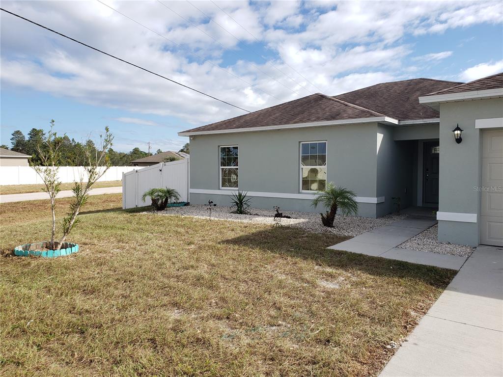 A light green house exterior with a brown roof, white trim, and a small front yard — 100 SWEET PEA COURT, POINCIANA, FL