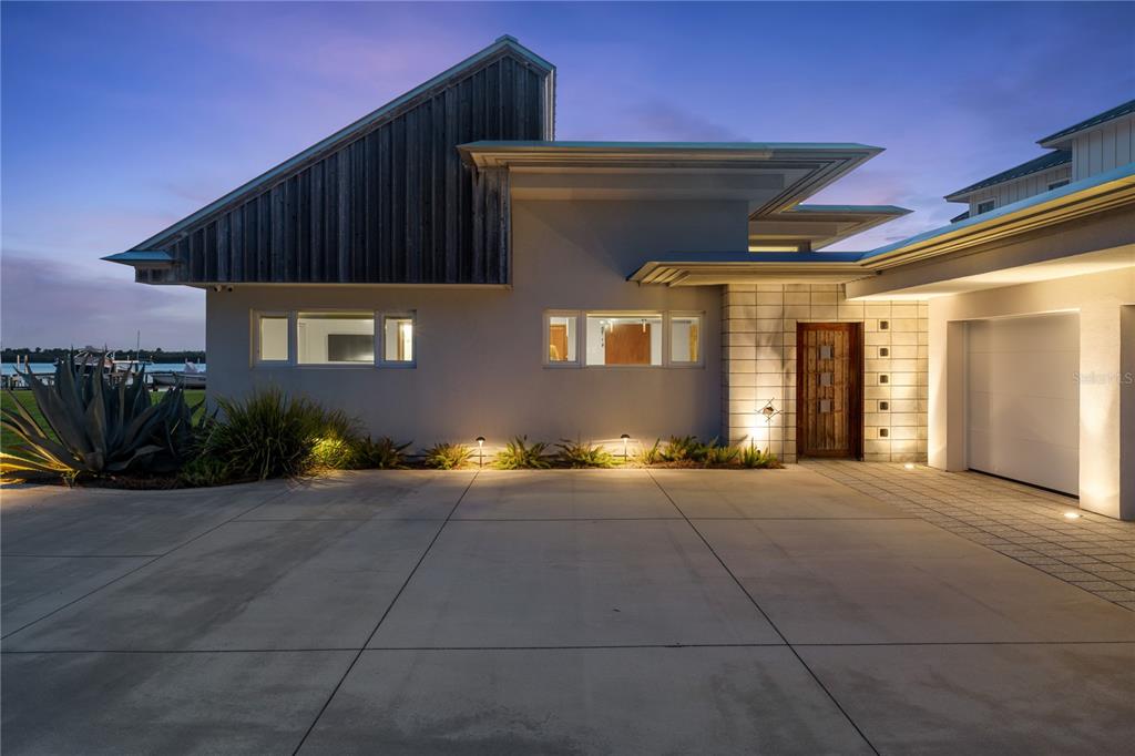 A modern house exterior features a concrete driveway, a wooden front door, and vertical siding — 1800 N INDIAN RIVER ROAD, NEW SMYRNA BEACH, FL