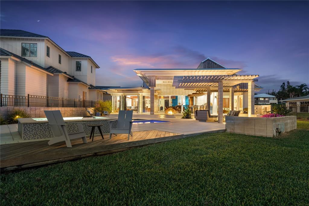 A modern house exterior at dusk featuring a pool, hot tub, and covered patio area — 1800 N INDIAN RIVER ROAD, NEW SMYRNA BEACH, FL