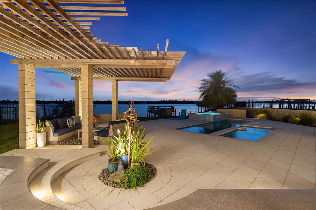 A patio with a wooden pergola, outdoor seating, a swimming pool, and a waterfront view — 1800 N INDIAN RIVER ROAD, NEW SMYRNA BEACH, FL