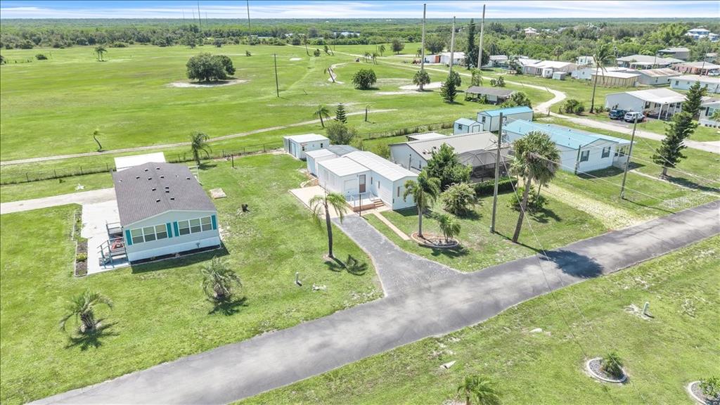 An aerial view shows several manufactured homes situated on a large, grassy lot with trees — 1235 MADONA COURT, PUNTA GORDA, FL