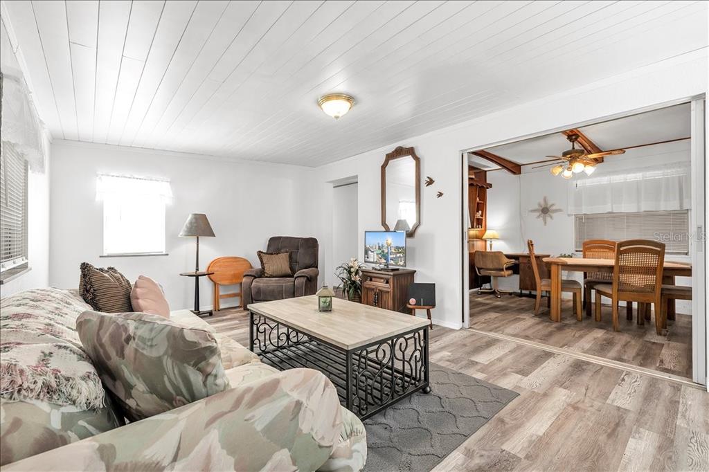 A living room with wood-look flooring and a dining area visible through a sliding door — 1235 MADONA COURT, PUNTA GORDA, FL